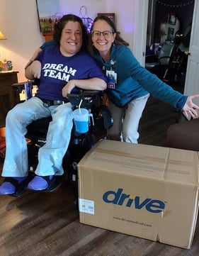 Emily sits smiling in her wheelchair next to her PT and the small box for the Drive Med-Aire Low Loss Mattress